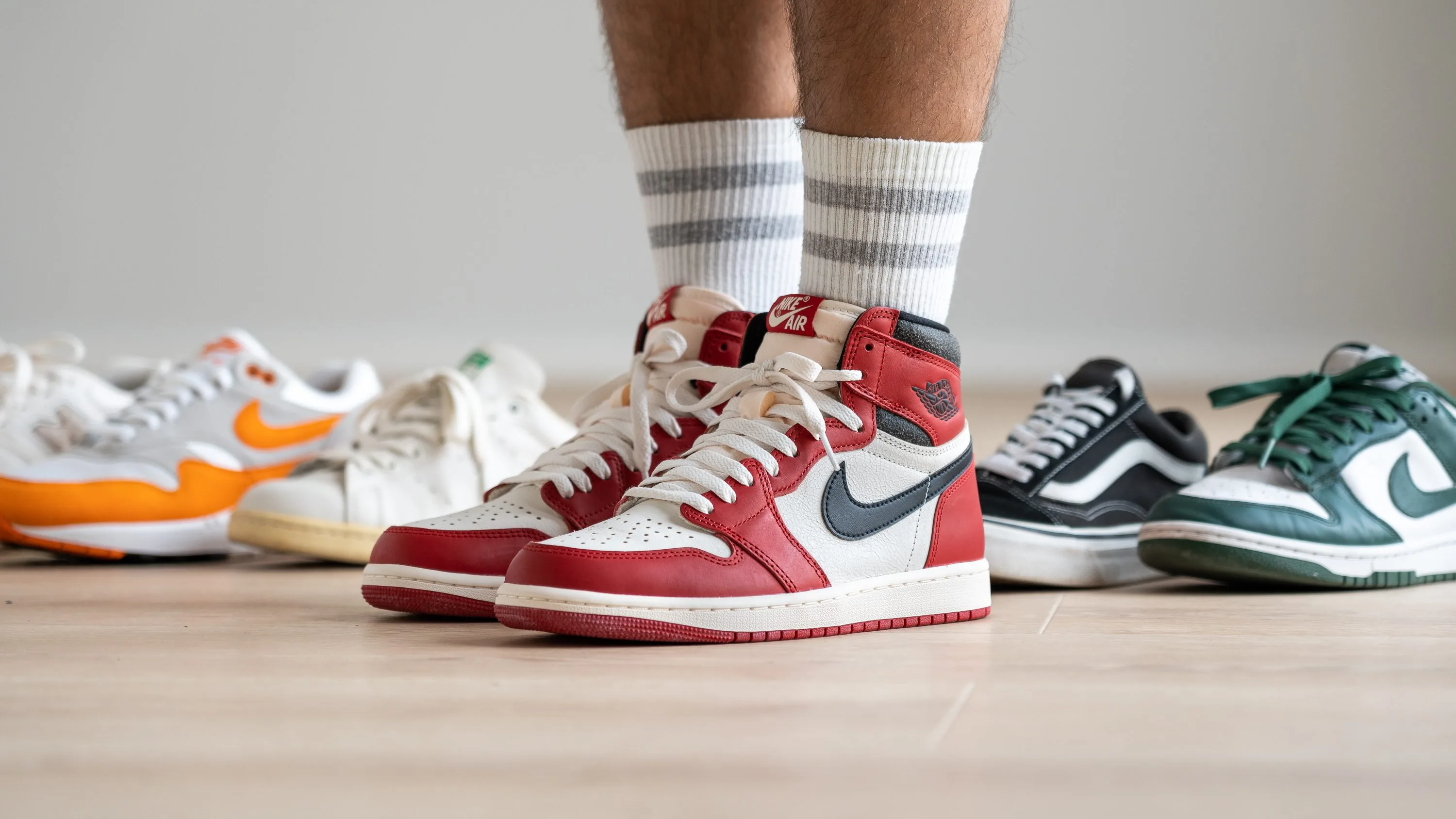 A collection of essential sneakers featuring Air Jordan 1 High 'Chicago' on-foot, Nike Air Max 1, Adidas Stan Smith, Vans Old Skool, and Nike Dunk Low 'Spartan Green